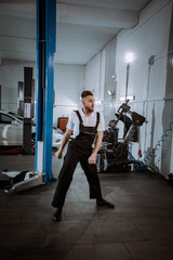 Fototapeta premium Attractive mechanic man in a modern service center dancing funny in front of the camera he take a break from work