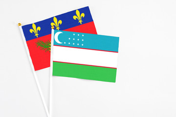 Uzbekistan and Guadeloupe stick flags on white background. High quality fabric, miniature national flag. Peaceful global concept.White floor for copy space.