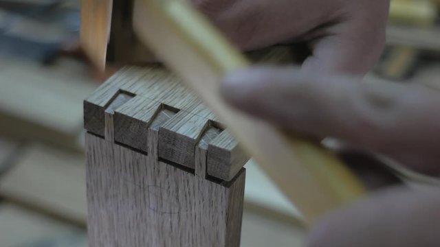 a joiner in an apron cuts a dovetail joint