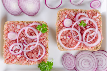 german sandwich mettbrotchen, bun and raw meat with onion and parsley, closeup
