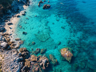 Naklejka na ściany i meble Aerial view of Tropea beach, crystal clear water and rocks that appear on the beach. Calabria, Italy. Swimmers, bathers floating on the water. Coastline of Calabria