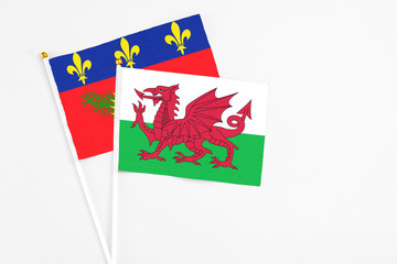 Wales and Guadeloupe stick flags on white background. High quality fabric, miniature national flag. Peaceful global concept.White floor for copy space.