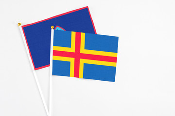 Aland Islands and Guam stick flags on white background. High quality fabric, miniature national flag. Peaceful global concept.White floor for copy space.