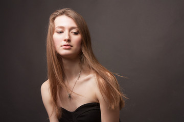 portrait girl in a Studio with on a dark background with long hair, open shoulders and cleavage.