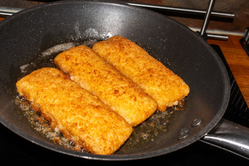 fresh fried crispy fish fillets with breading in a pan
