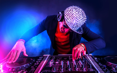 Young Dj playing on the turntable in the night club