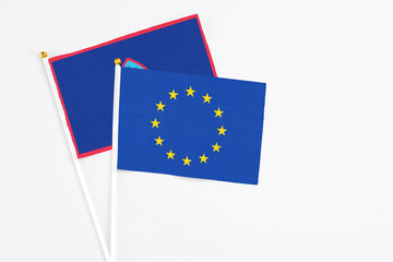 European Union and Guam stick flags on white background. High quality fabric, miniature national flag. Peaceful global concept.White floor for copy space.