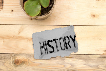 word history on cardboard with plant on wooden table