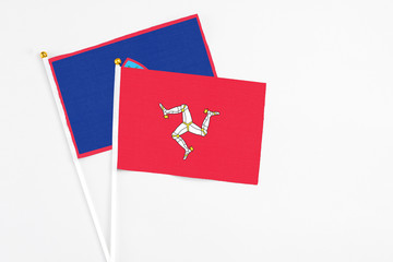 Isle Of Man and Guam stick flags on white background. High quality fabric, miniature national flag. Peaceful global concept.White floor for copy space.