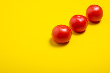 Red tomatoes fresh on yellow background, top view