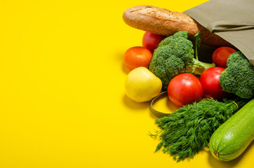 Food vegetable, bread, fruit in eco grocery bag on yellow background, top view