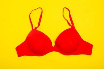Red push up bra on yellow background, top view