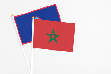 Morocco and Guam stick flags on white background. High quality fabric, miniature national flag. Peaceful global concept.White floor for copy space.