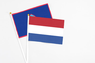 Netherlands and Guam stick flags on white background. High quality fabric, miniature national flag. Peaceful global concept.White floor for copy space.