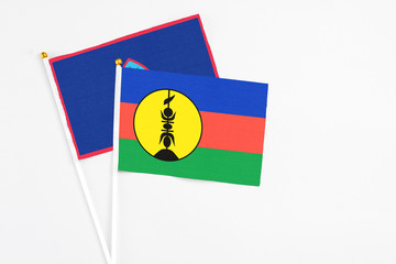New Caledonia and Guam stick flags on white background. High quality fabric, miniature national flag. Peaceful global concept.White floor for copy space.