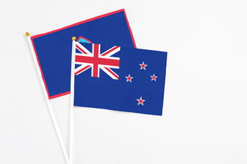 Fototapeta premium New Zealand and Guam stick flags on white background. High quality fabric, miniature national flag. Peaceful global concept.White floor for copy space.