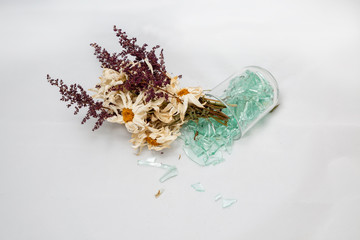 wilted bouquet, dry old flowers in a broken glass vase. concept of autumn, broken dreams, white background