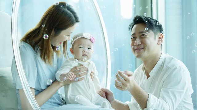 Adorable Chinese baby enjoying curious floating soap bubbles