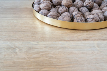 Walnuts on a natural oak wooden background. A natural perspective composition in brown and gold  colors. Blank space in left corner.