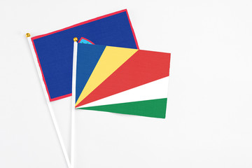 Seychelles and Guam stick flags on white background. High quality fabric, miniature national flag. Peaceful global concept.White floor for copy space.