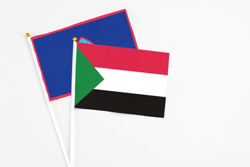 Sudan and Guam stick flags on white background. High quality fabric, miniature national flag. Peaceful global concept.White floor for copy space.
