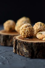 Vegan snack concept. Homemade frozen oatmeal balls with pumpkin seeds on oak wood slabs on black background copy space