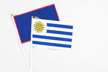 Uruguay and Guam stick flags on white background. High quality fabric, miniature national flag. Peaceful global concept.White floor for copy space.