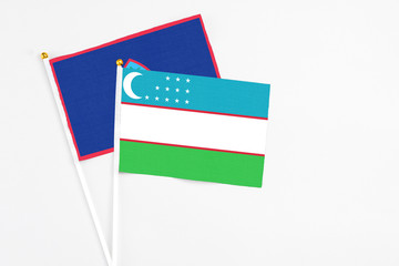 Uzbekistan and Guam stick flags on white background. High quality fabric, miniature national flag. Peaceful global concept.White floor for copy space.