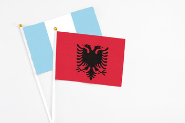 Albania and Guatemala stick flags on white background. High quality fabric, miniature national flag. Peaceful global concept.White floor for copy space.