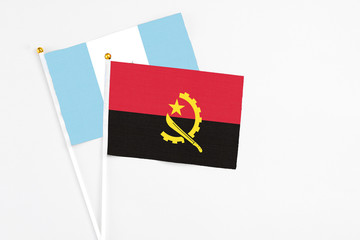Angola and Guatemala stick flags on white background. High quality fabric, miniature national flag. Peaceful global concept.White floor for copy space.