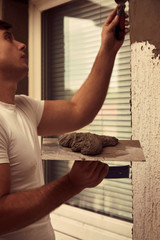 Construction worker plaster a wall.