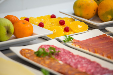 varios platos de fruta,salchichon,jamon y naranja