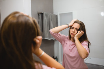 sleepy woman looking in the mirror in bathroom