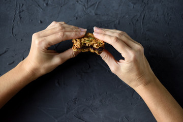 Dieting or vegan food concept. Slender woman hands holding oatmeal breakfast cookie sandwich with...