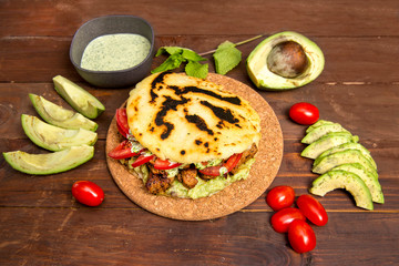 Arepas - Traditional Colombian Food originally from Latin America arranged on a old rustic wooden table mixed with meat, vegetable and special avocado sauce. Image from above