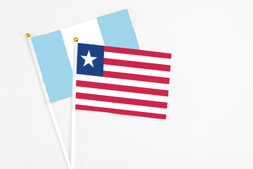 Liberia and Guatemala stick flags on white background. High quality fabric, miniature national flag. Peaceful global concept.White floor for copy space.