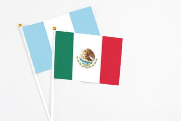 Mexico and Guatemala stick flags on white background. High quality fabric, miniature national flag. Peaceful global concept.White floor for copy space.