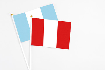 Peru and Guatemala stick flags on white background. High quality fabric, miniature national flag. Peaceful global concept.White floor for copy space.