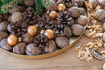 Merry Christmas decoration  with walnuts on a natural oak wooden background. A natural perspective composition in brown and gold  colors. 