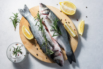 Fresh raw wild sea bass with herbs and spices on wooden cutting board top view. Healthy and organic food concept. Seafood concept.