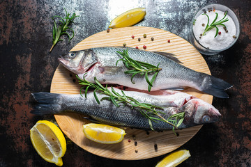 Fresh wild sea bass with spices, herbs and sea salt on the kitchen table top view. Healthy and organic food concept.
