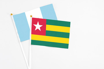 Togo and Guatemala stick flags on white background. High quality fabric, miniature national flag. Peaceful global concept.White floor for copy space.