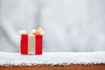 red winter Christmas gift box in snow background outdoors.