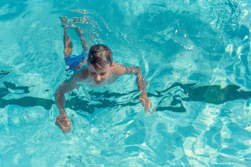 Obraz na płótnie Canvas Learning to swim. Boy swimming along the side of pool.