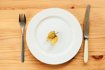 White plate and knife with a fork are served on a wooden table. view from above.