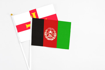 Afghanistan and Guernsey stick flags on white background. High quality fabric, miniature national flag. Peaceful global concept.White floor for copy space.
