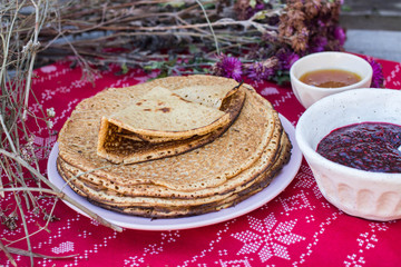 Crepes or traditional Russian pancakes with honey on Christmas tablecloth. Homemade.