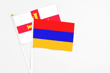 Armenia and Guernsey stick flags on white background. High quality fabric, miniature national flag. Peaceful global concept.White floor for copy space.