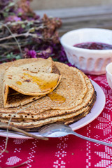 Crepes or traditional Russian pancakes with honey on Christmas tablecloth. Homemade.