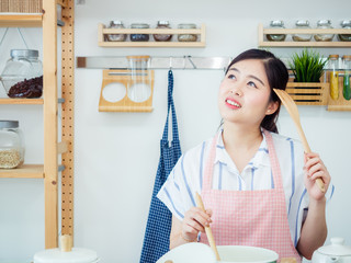 Asian woman in kitchen.smile teeth girl wearing pin apron with fruit and tablet on table prepare...